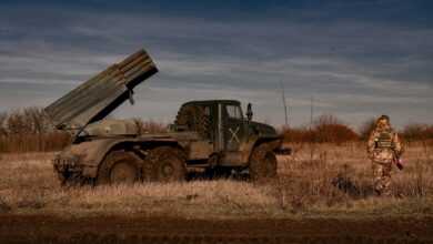 a man standing in a field next to a truck