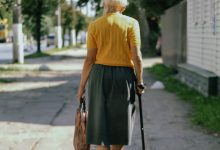 a woman walking down a sidewalk with a cane
