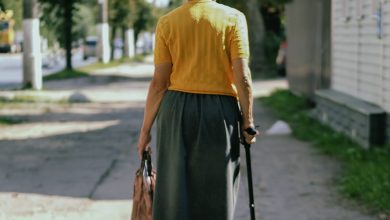 a woman walking down a sidewalk with a cane