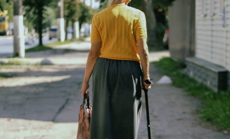 a woman walking down a sidewalk with a cane